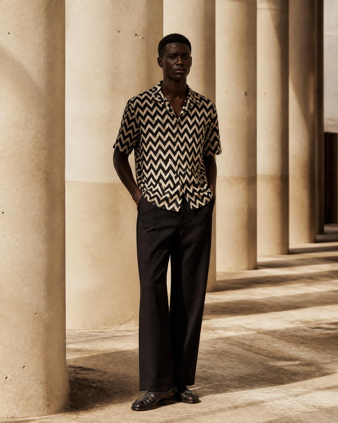 African model wearing the Black & White Zigzag Printed Camp Collar Shirt in a sunlit colonnade